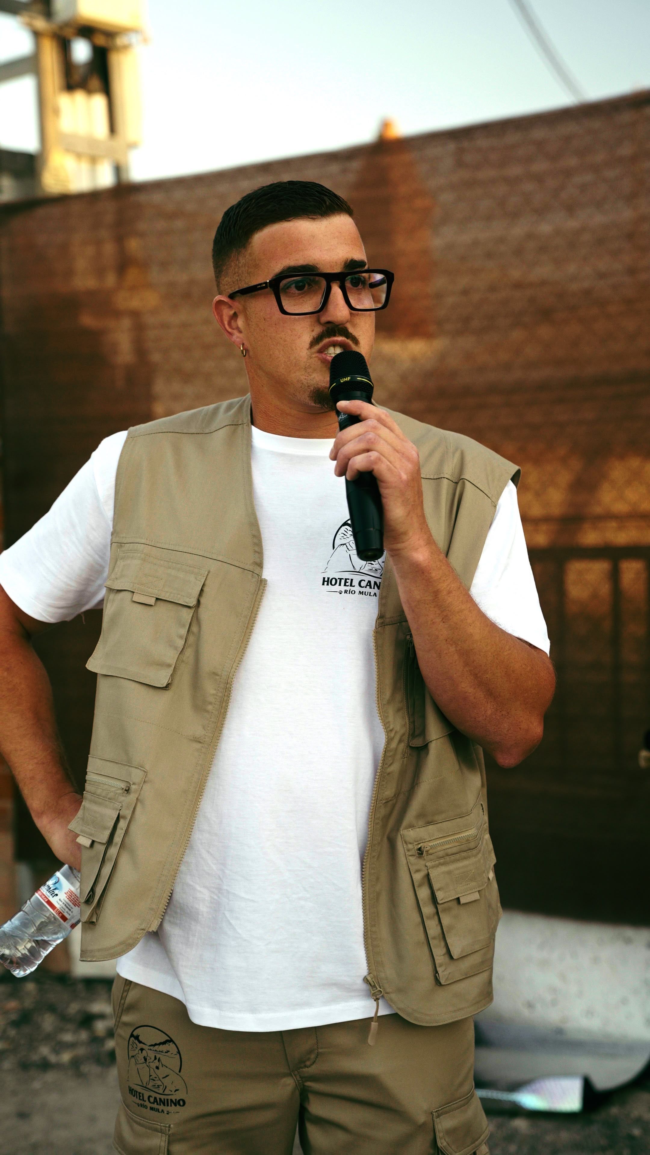 La misma intervención con micrófono de mano, en plano medio y con el encuadre más centrado sobre la camiseta serigrafiada.