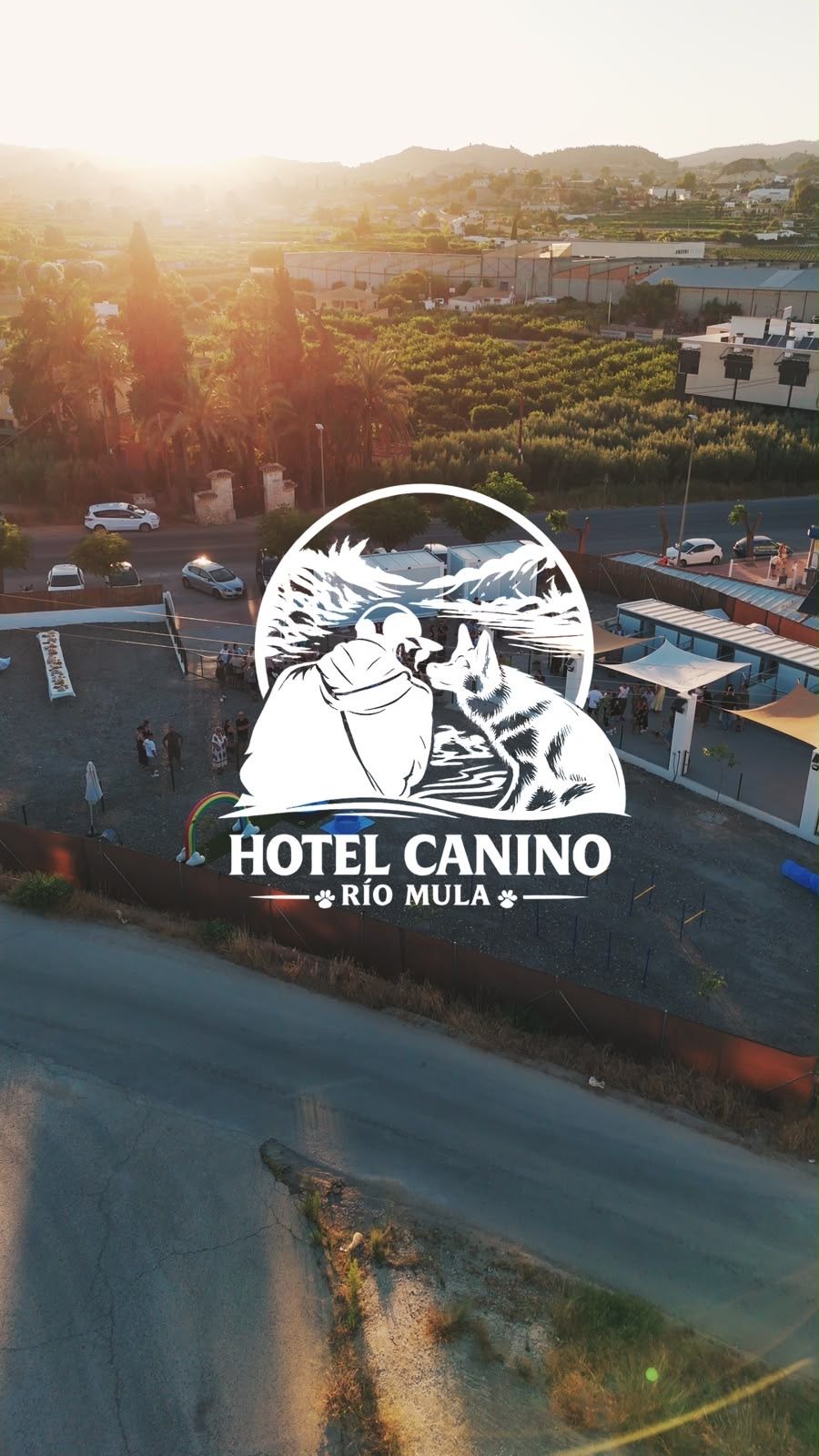 Vista aérea del recinto al atardecer, con el logotipo de Hotel Canino Río Mula superpuesto en blanco sobre el centro de la imagen.